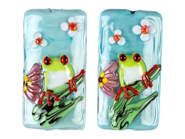 Create lively style with this Grace Lampwork bead. This bead features a rectangular shape and a puffed dimension that will stand out in your jewelry designs. Both sides are decorated with a bright green tree frog staring with red eyes. The frog sits on a green branch surrounded by sweet pink and white flowers on a soft blue background. String this bead onto a head pin for a quick pendant, use it at the center of a bold bracelet style, and more. It will add cheerful beauty anywhere.This item is handmade, so appearances may vary.38.0 x 20.0mm