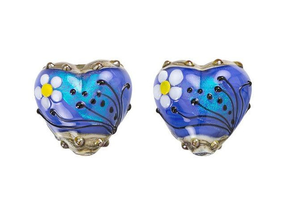 Add a lovely artistic touch to designs with this Grace Lampwork bead. This bead features a sweet heart shape with a puffed dimension. Both sides of the bead are decorated with a white and yellow daisy and black swirls and dots. The inside of the glass shimmers with an elegant powder blue color that lights up with aqua glitter. You can string this bead onto a head pin to turn it into a pendant or try it on a beaded strand. This item is handmade, so appearances may vary.