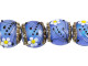 Transform your jewelry into a natural wonderland with the Grace Lampwork Arctic Blue Florals Lentil Bead Strand. These exquisite glass beads are delicately crafted into a circular lentil shape, with the appearance of a subtle puffed dimension. The surface is beautifully adorned with a white and yellow daisy with black swirls and dots, designed to capture the essence of nature. From every angle, these beads radiate a radiant powder blue color that shimmers with aqua glitter. Add these beads to your collection and create captivating pieces that showcase your creative spirit. Embrace the beauty of nature and elevate your craftsmanship to new heights.