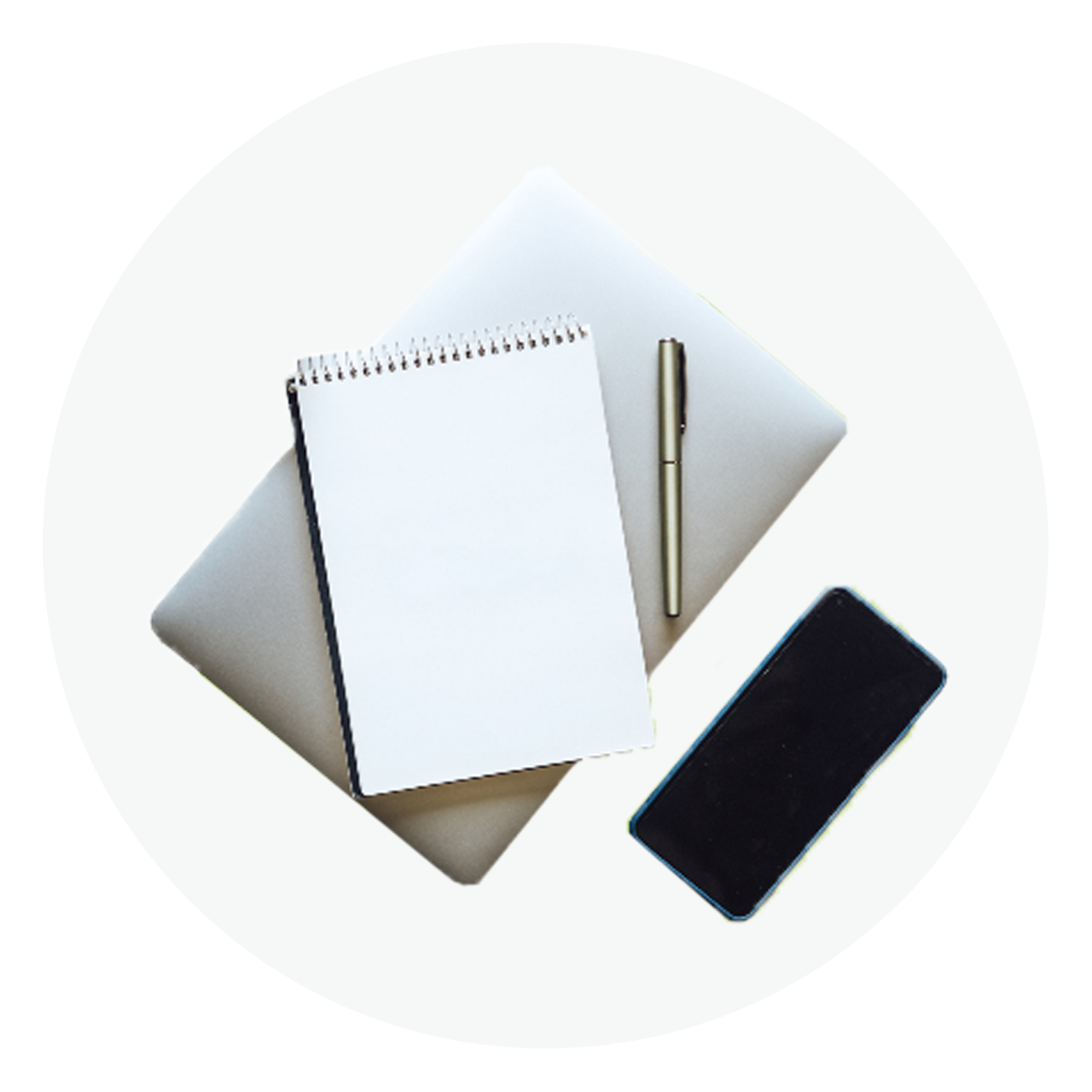 Notebook, pen, laptop, and smartphone arranged in a minimalist overhead layout.