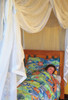 Cotton box mosquito net draped over a single bed