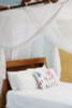 Cotton box mosquito net draped over a double bed lifestyle view