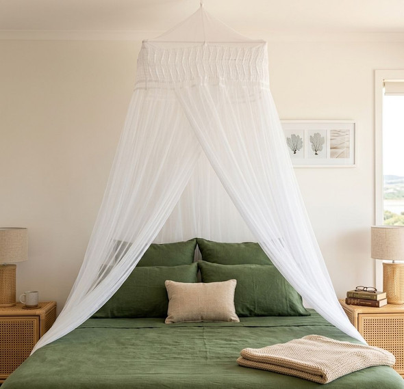 Cotton mosquito net bed canopy draped over a bed with green bedding
