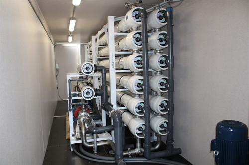 Twelve Pentair Codeline pressure vessels racked six by two inside the ForeverPure SWRO-HE-1000TPD container, with the high-pressure pump and stainless manifold at floor level
