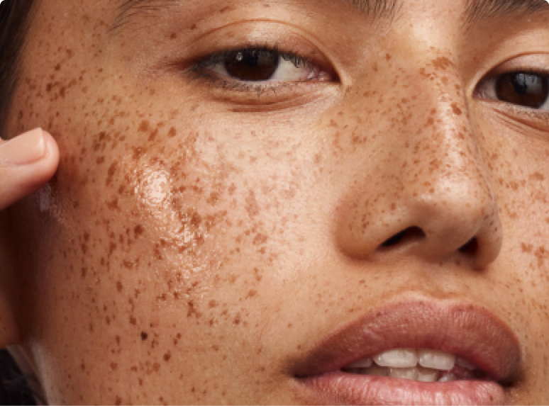 Female Asian-American model with light pink manicured nails applying moisturizer as step 3 - the last step - of her skin care routine.