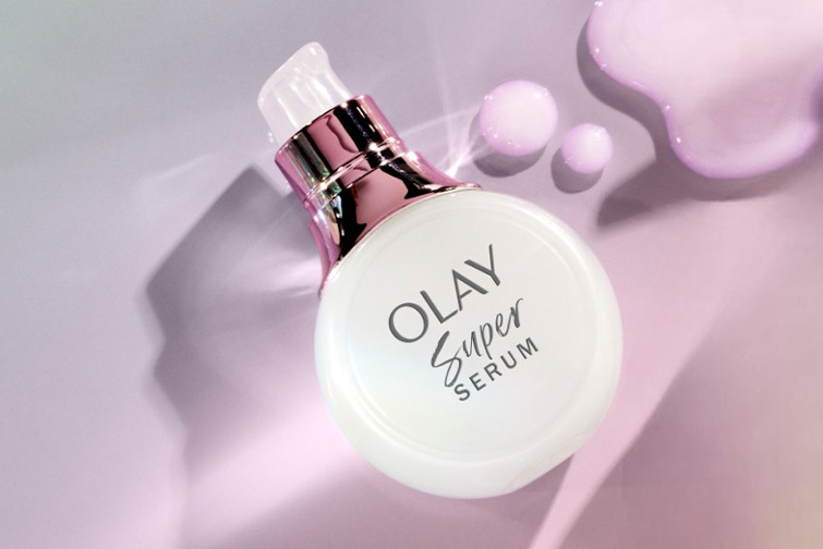 Bottle of Olay Super Serum laying diagonally on a violet table