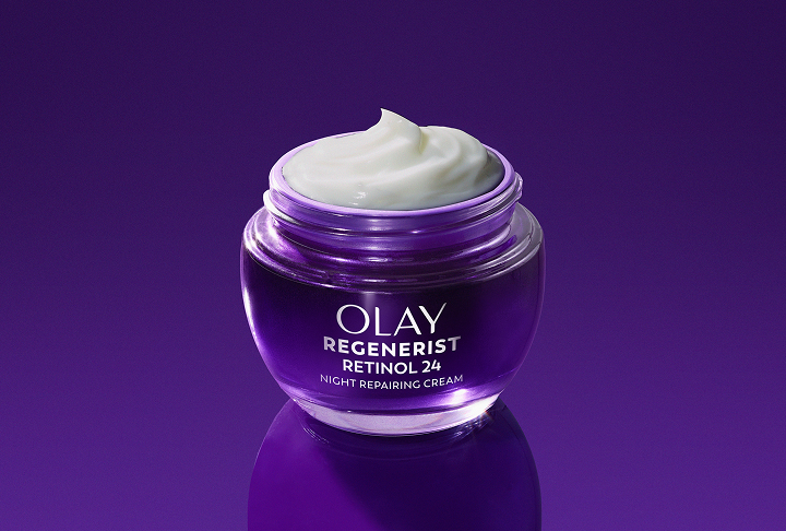  Deep purple glass jar of Olay Retinol24 Night Face Moisturizer posed on a dark purple background