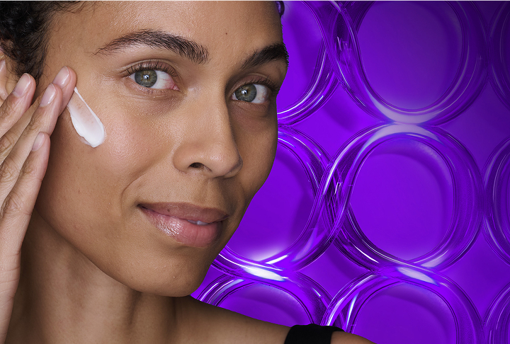 Smiling woman applying Olay Retinol 24 Night Face Moisturizer Cream on her right cheek.