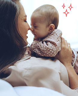 A mother holder her baby girl and touching noses