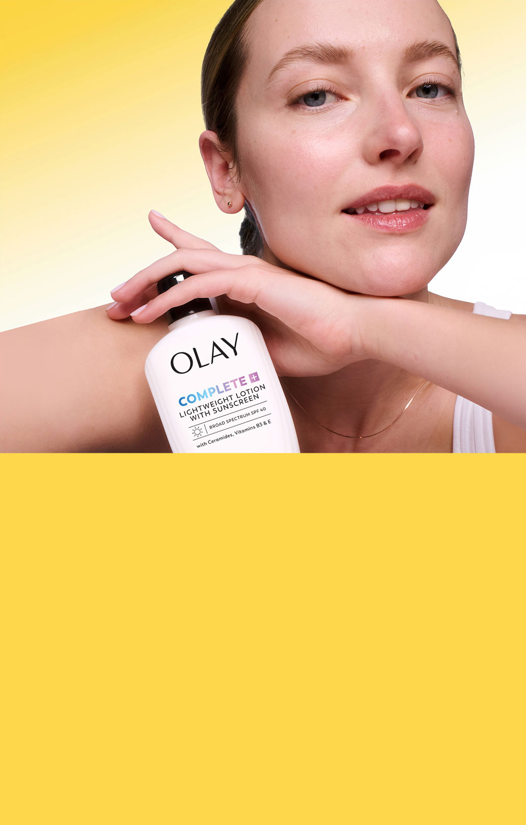 Smiling woman with dewy, natural skin holding a bottle of Olay Complete Lightweight Lotion with SPF 30 against her cheek, set against a yellow-to-white gradient background resembling a sunny day.