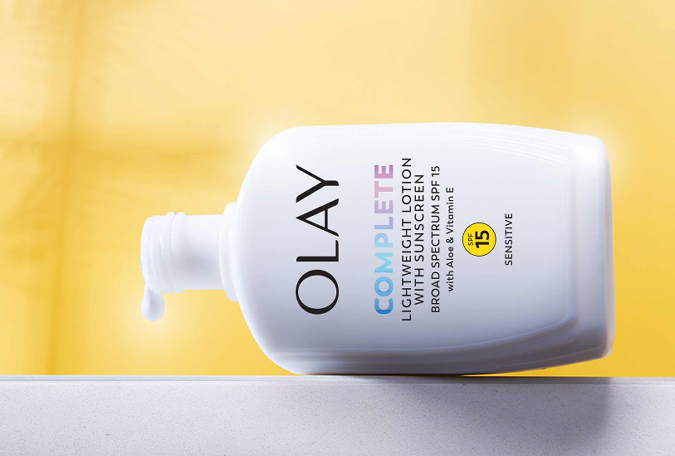 Bottle of Olay Complete Sensitive SPF 15 posed on a white marble countertop with its lid removed and a drop of the moisturizer coming out to shows its white texture. Bottle of Olay Complete Sensitive SPF 15 posed on a white marble countertop with its lid removed and a drop of the moisturizer coming out to shows its white texture.