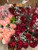 Assorted colors of pink and red rose bouquets with green filler and baby's breath