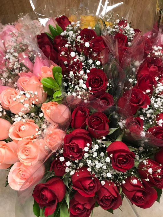 Assorted colors of pink and red rose bouquets with green filler and baby's breath