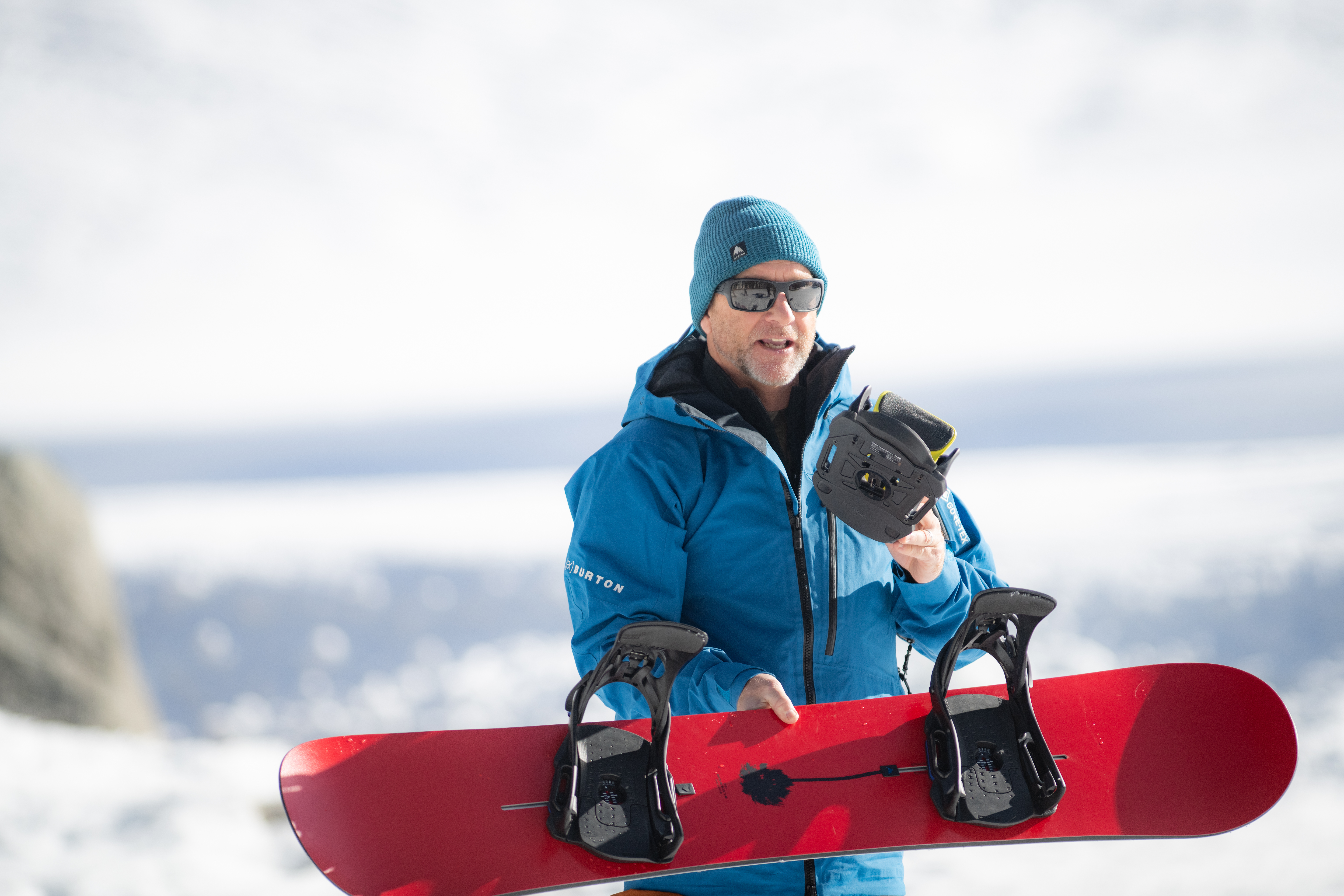 man holding snowboard showing bindings