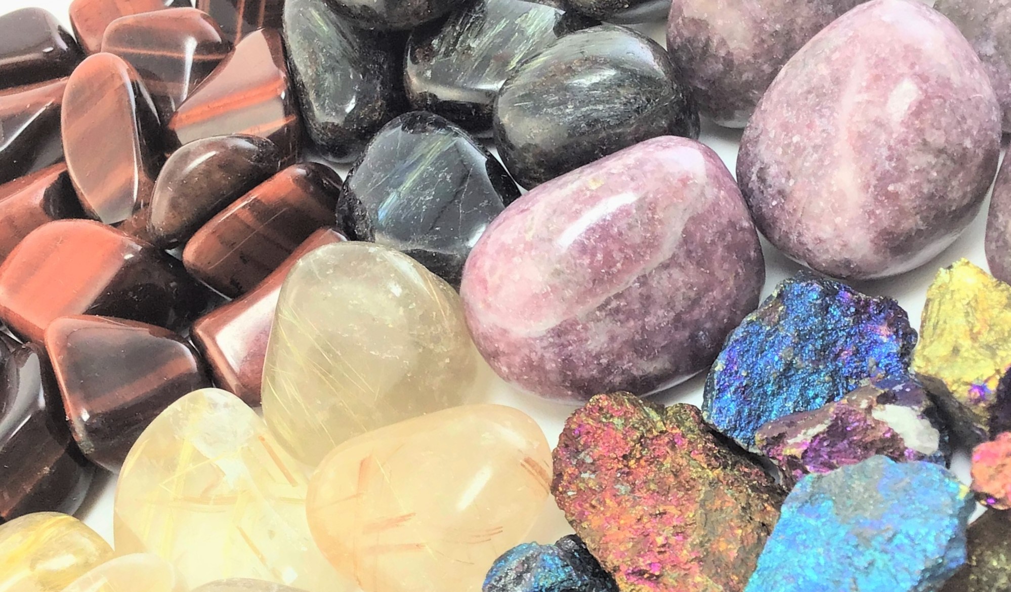 Tumbled crystals for New Years in a radial pattern, including Arfvedsonite, Chalcopyrite, Lepidolite, Red Tiger's Eye, and Rutilated Quartz.