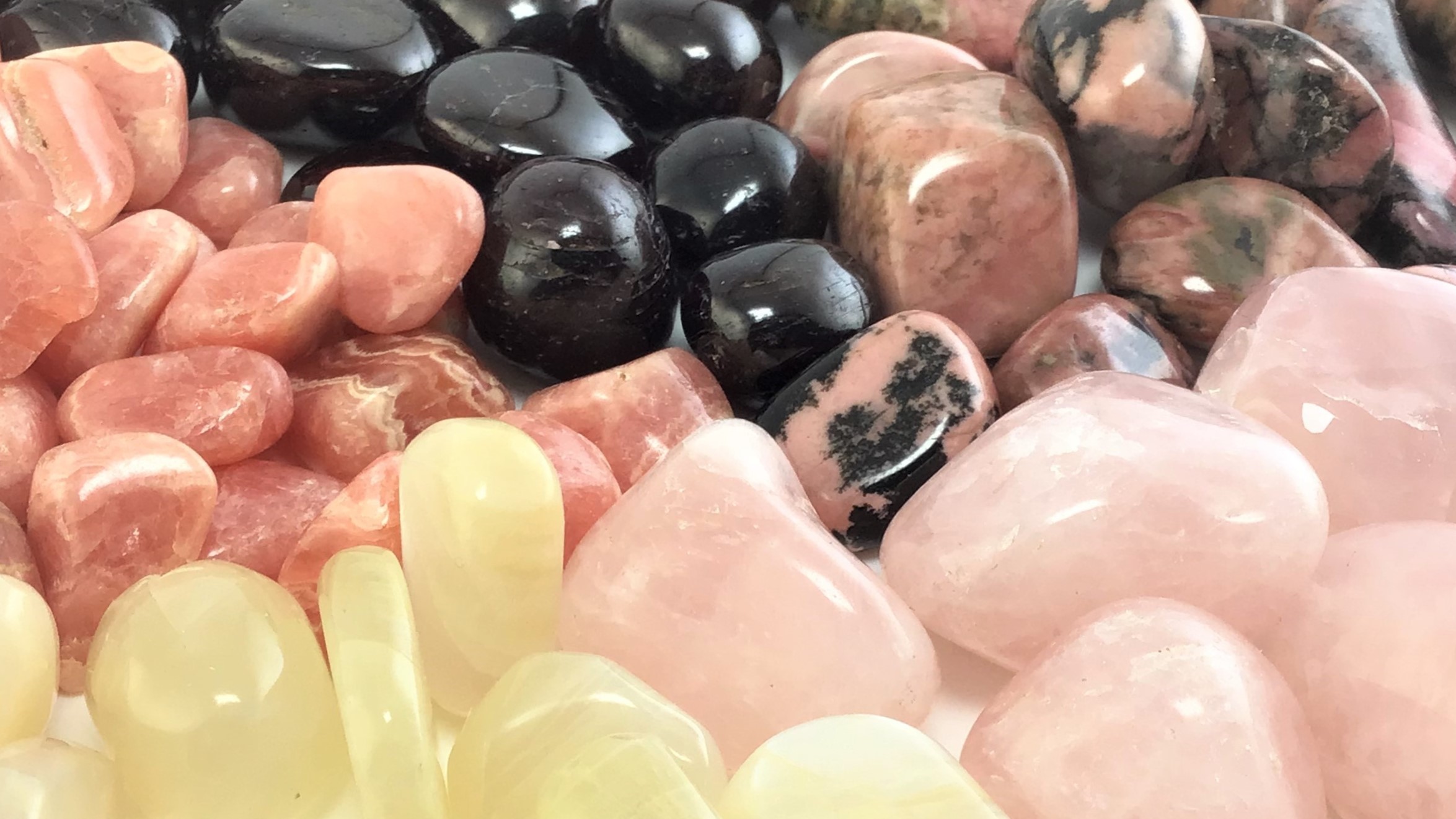 Tumbled crystals for Valentine's Day in a radial pattern, including Garnet, Peach Moonstone, Rose Quartz, Rhodochrosite, and Rhodonite.