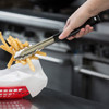 A hand holding Black Stainless Steel Serving Tongs picking up fries.
