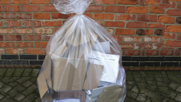 Full up Clear Refuse Sack against a brick wall outside.