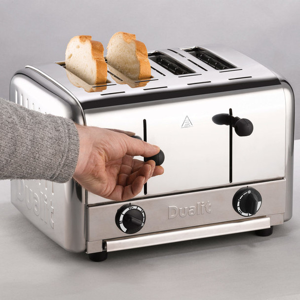 Full shot of Dualit Caterers Pop-up Toaster with 2 toasted bread and a hand operating it.