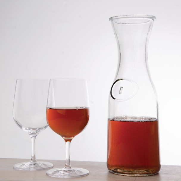 Olympia Glass Carafe 1Ltr with content together with two wine glass, one is empty and the other one has content.