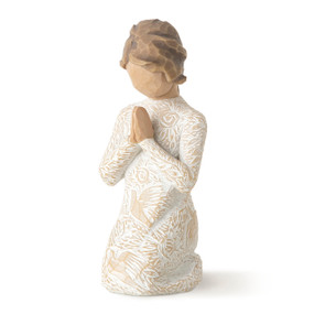 Front view of kneeling female figure with brown wavy hair and hands in prayer pose, cream dress carved with birds and flowers