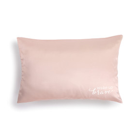 light pink satin pillowcase with white letters in bottom right corner reading Wake Up Brave