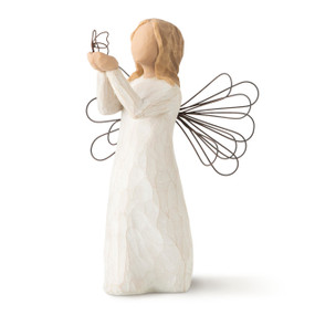 Left view of standing female figure in cream dress with wire wings, holding out wire butterfly in extended hands