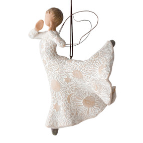 Left view of figure in cream dress carved with celestial patterns in ballet pose with hands raised to mouth and leg up behind her, wire wings on back and ornament hook on head