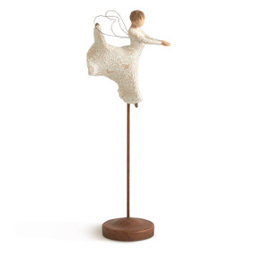 Front view of figure in ballet pose with wire wings in cream dress carved with natural patterns, figure elevated on metal stand with base