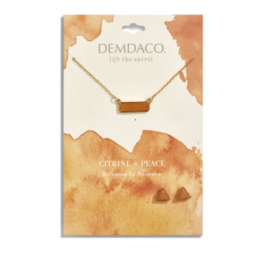 Gold necklace holds a rectangular pendant with a yellow stone. Two gold, triangular stud earrings have yellow stones. Both necklace and earrings are on a white message card with yellow accents