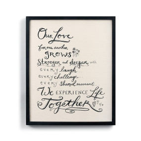 white wall hanging with poem about love written in black handwriting font inside black frame