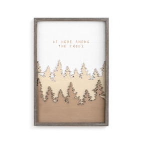 A gray frame enclosing a brown forest wall art piece that reads "at home among the trees".