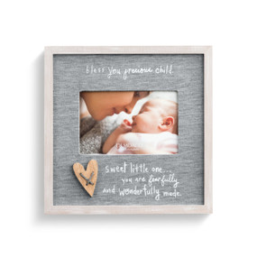 A gray picture frame with a cloth gray heather backing, a wooden heart, and reads bless you precious child, sweet little one... you are fearfully and wonderfully made". Enclosed in a light wooden frame. Enclosing a picture of a mom and newborn baby."