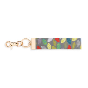 A gray and multi color leaf print wrist strap with gold metal accents.