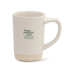 A cream stoneware handled mug with a tan textured base that says "Where America is still Wild".