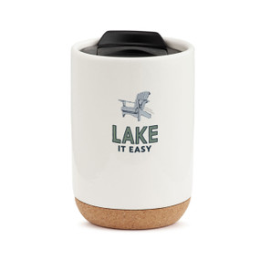 A white stoneware tumbler with a cork base and a plastic black lid. The tumbler has an image of blue Adirondack chair and the saying "Lake It Easy".