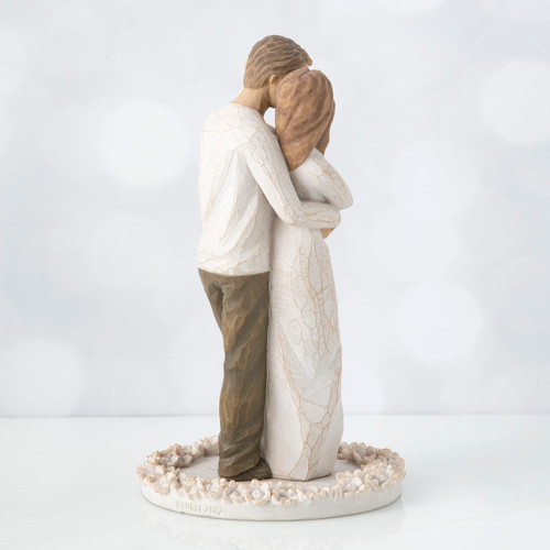 Man and woman figurine facing away from the front holding one another standing on round flower plaque