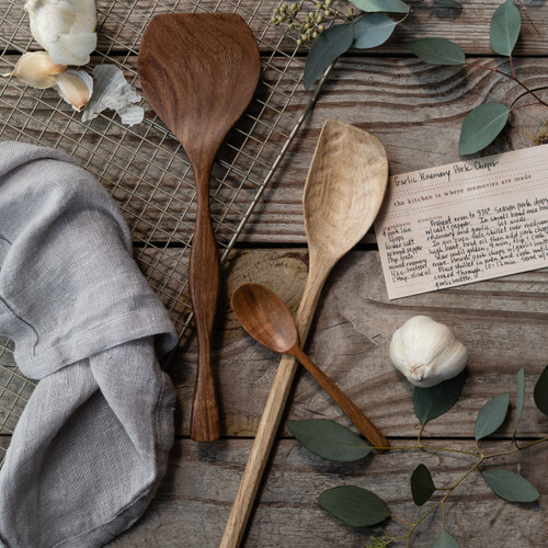 wooden spoons laid out on table next to recipe and ingredients and gray linen towel