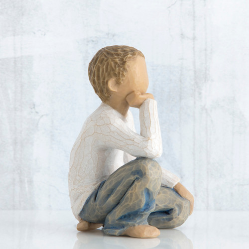 Side view of brunette boy figurine in white shirt and blue jeans kneeling