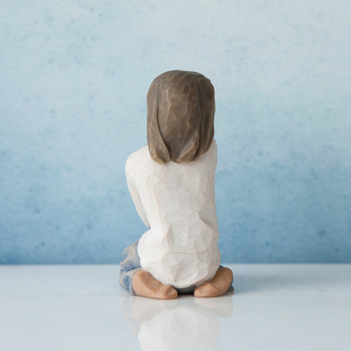 Back view of brunette girl figurine in white shirt kneeling down