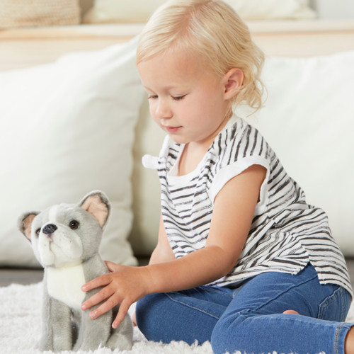 toddler sitting on floor holding stuffed dog