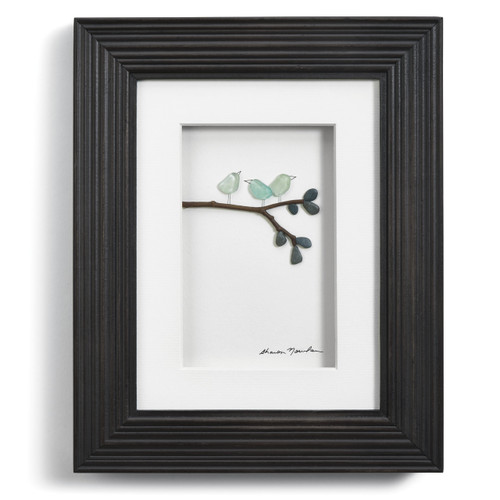Close view of black photo frame with white center and pebble birds on a branch