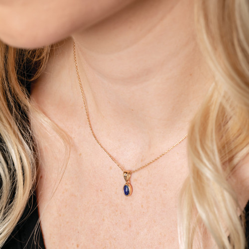 gold necklace charm with navy blue gem on gold chain