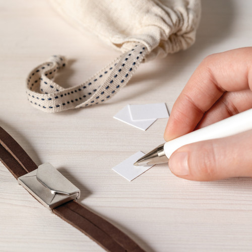 person writing on notes to put in envelope charm on bracelet