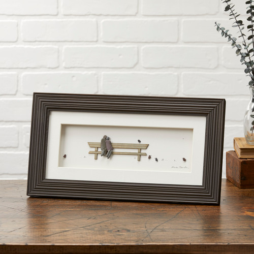 Wooden photo frame with pebble figuines sitting on bench