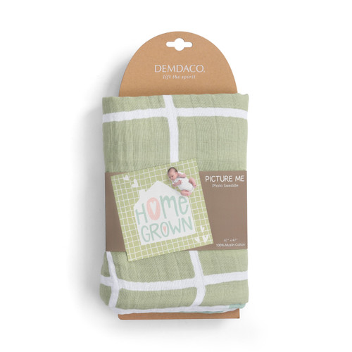 green baby swaddle blanket with words home grown and house illustration folded around product label card