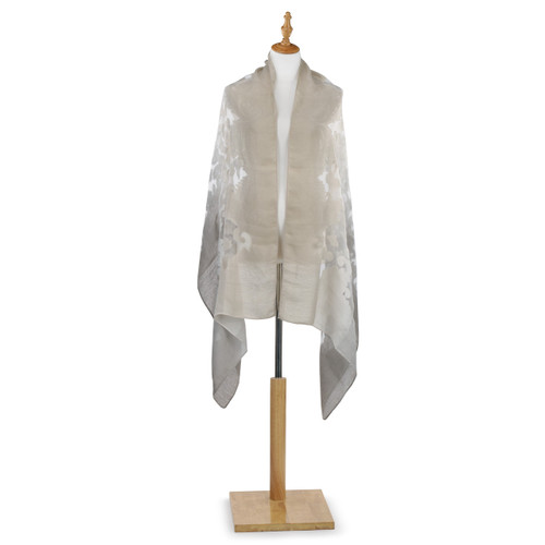 Far front view of tan shawl with white wooden stand