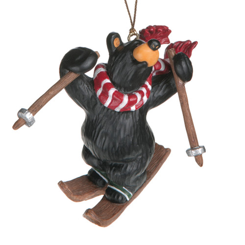 Small black bear figurine wearing red scarf holding wooden ski's