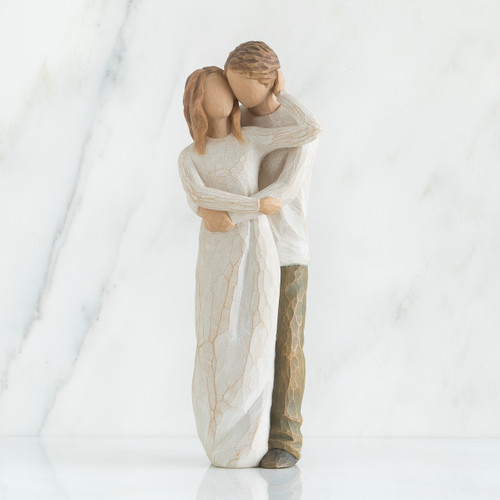 Faceless man and woman figurines with arms around each other - woman is wearing white dress, man is wearing white shirt with brown pants