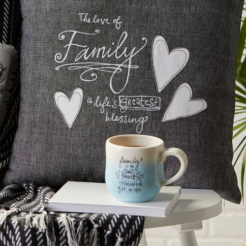 gray pillow and white and blue mug with phrases about family set up on white chair